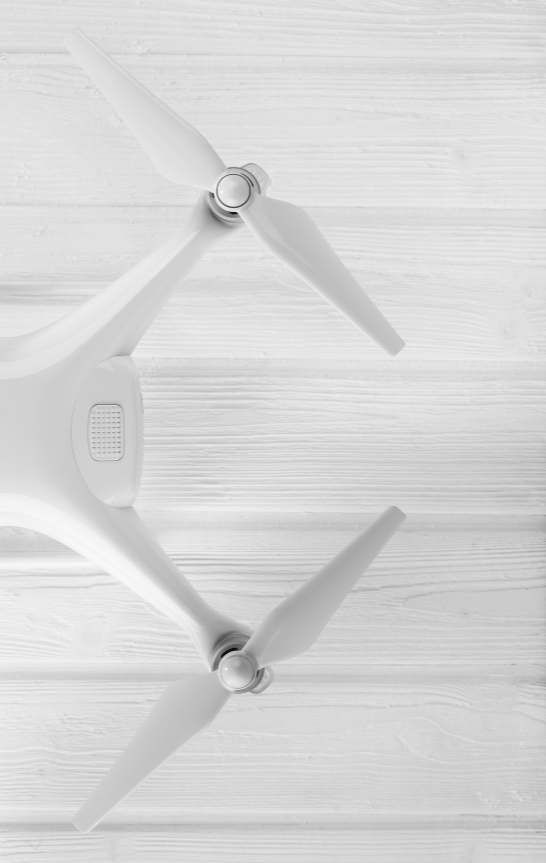 A white drone with two propellers resting on a light-colored wooden surface