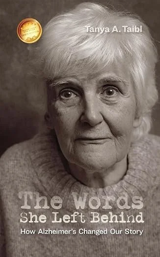 Book cover featuring a black and white photo of an elderly woman with short white hair, with the title 'The Words She Left Behind: How Alzheimer’s Changed Our Story' and author Tanya A. Taibl’s name, along with a gold seal.