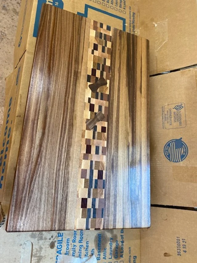 Wooden cutting board with the name 'LOVE' in the center, made of small wooden blocks of various shades.