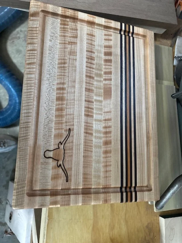 Wooden cutting board with a bird design and striped accents.