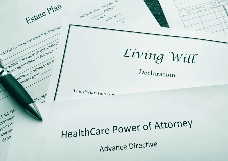 A collection of legal documents related to estate planning, including a Living Will and HealthCare Power of Attorney, with a pen resting on one of the papers.