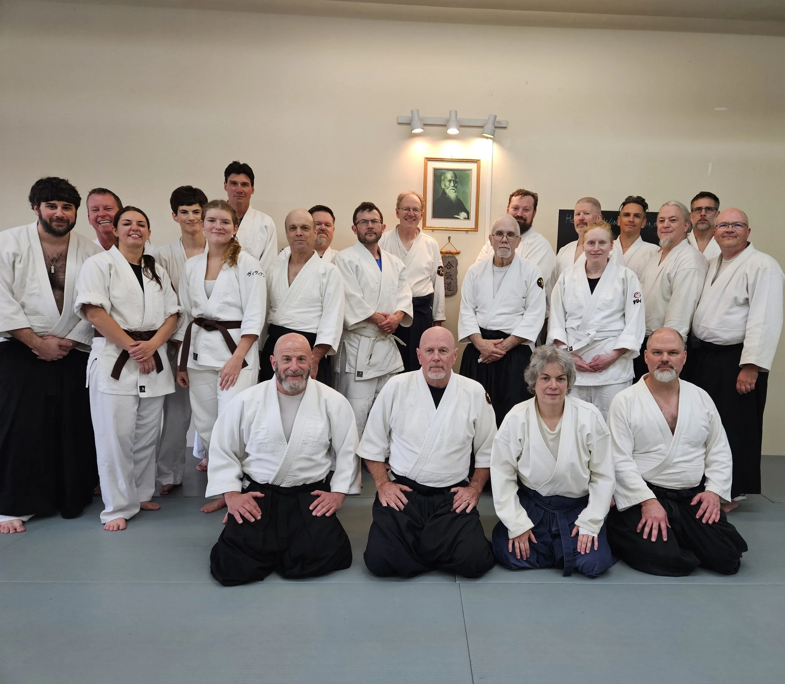 Group of people in martial arts uniforms posing together in a dojo.
