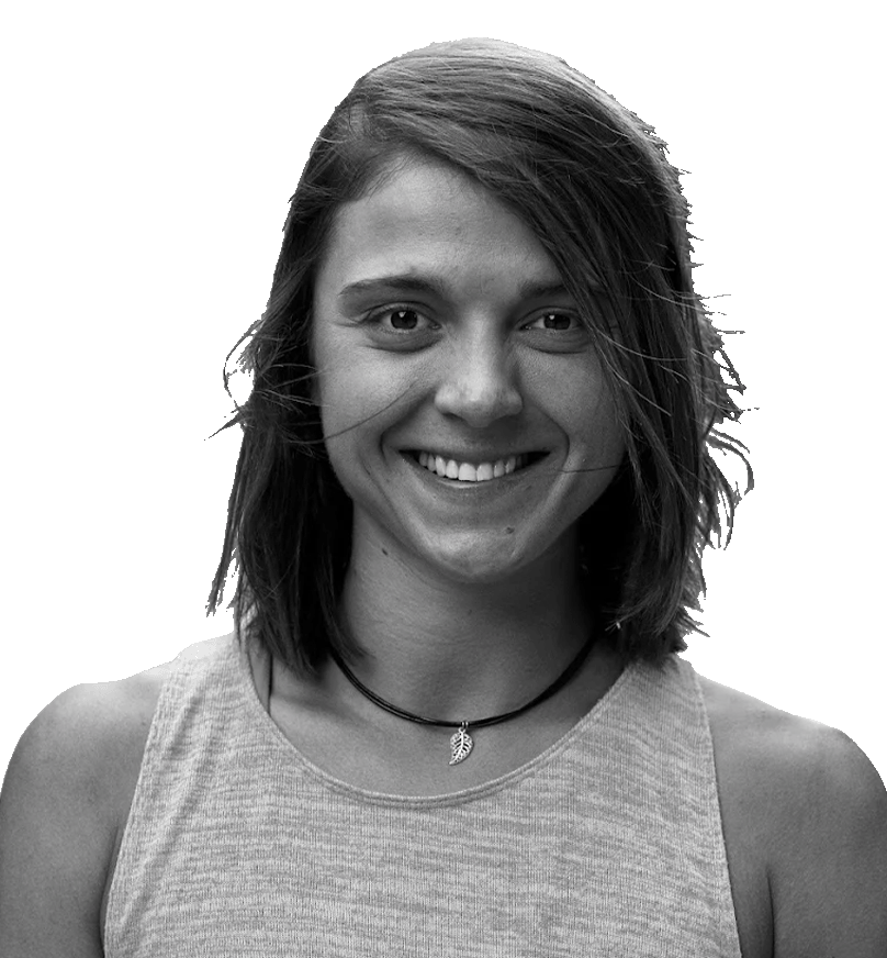 Black and white portrait of a young woman with shoulder-length hair, smiling, wearing a sleeveless top and a necklace with a leaf pendant.