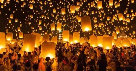 A large crowd of people releasing sky lanterns into the night sky during a festival or celebration.