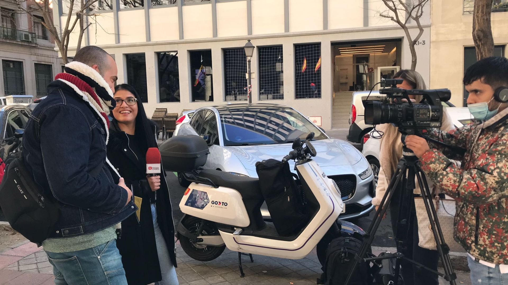 Un equipo de periodistas realiza una entrevista en la calle, con un microfono en mano y una cámara de video grabando.