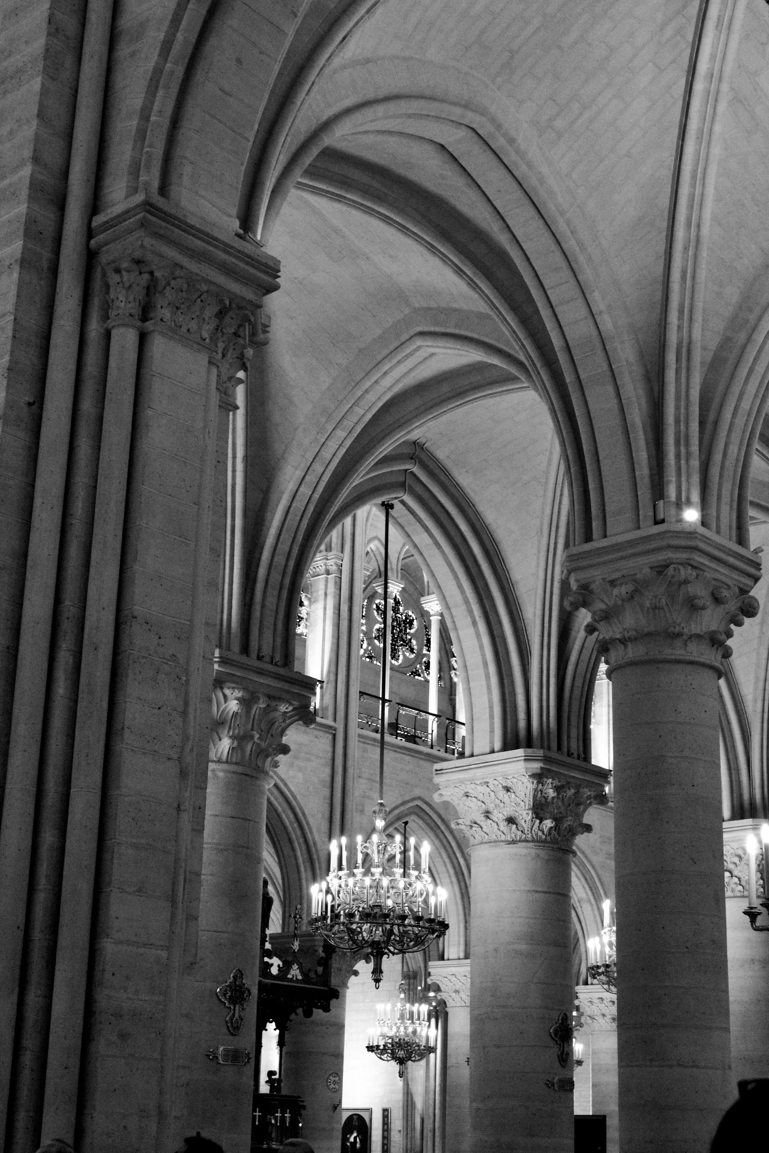 Interior of a Gothic cathedral with high vaulted ceilings, ornate columns, and chandeliers.