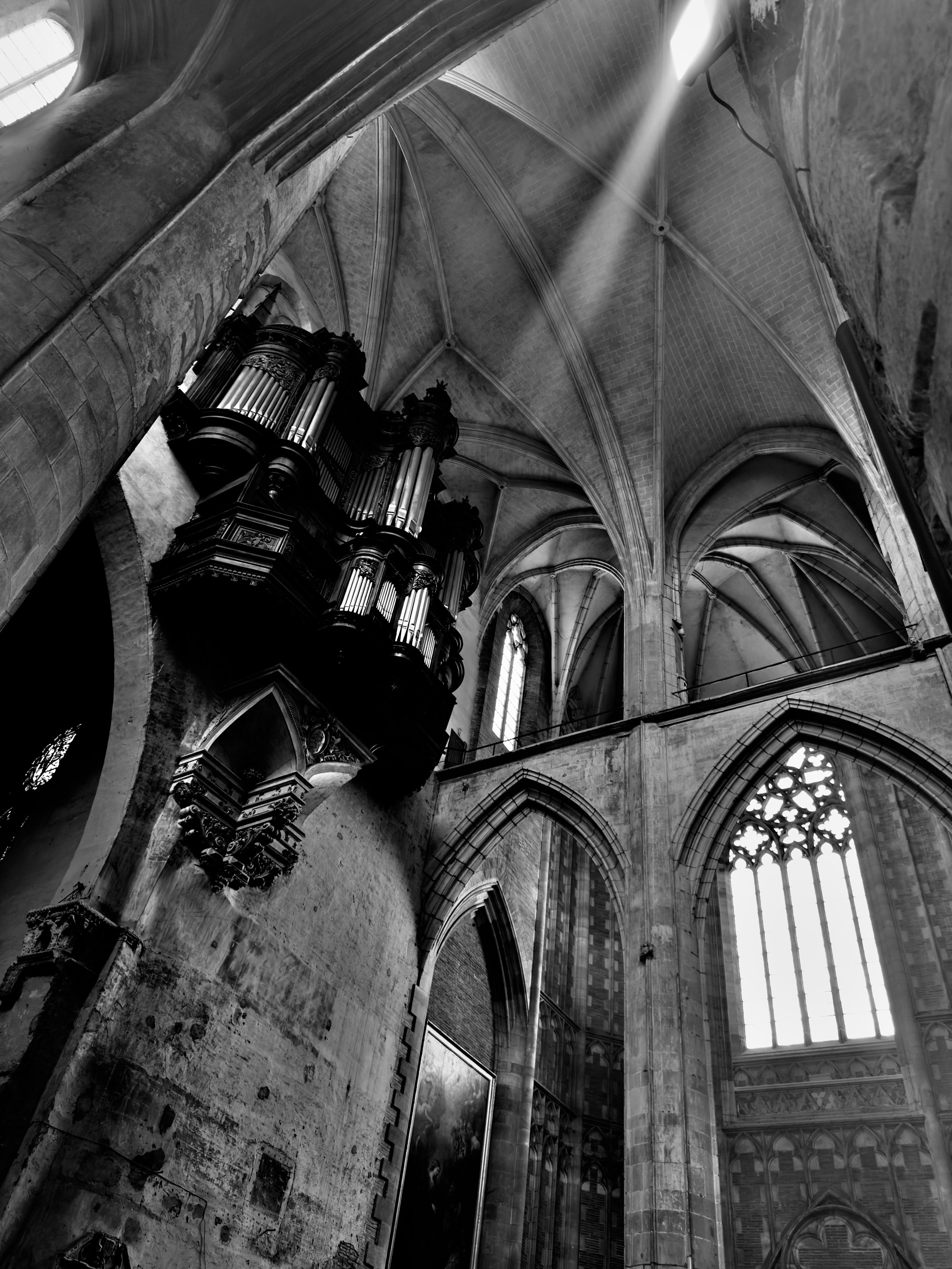 Interior of a Gothic cathedral with high vaulted ceilings, large stained glass windows, and an ornate pipe organ.