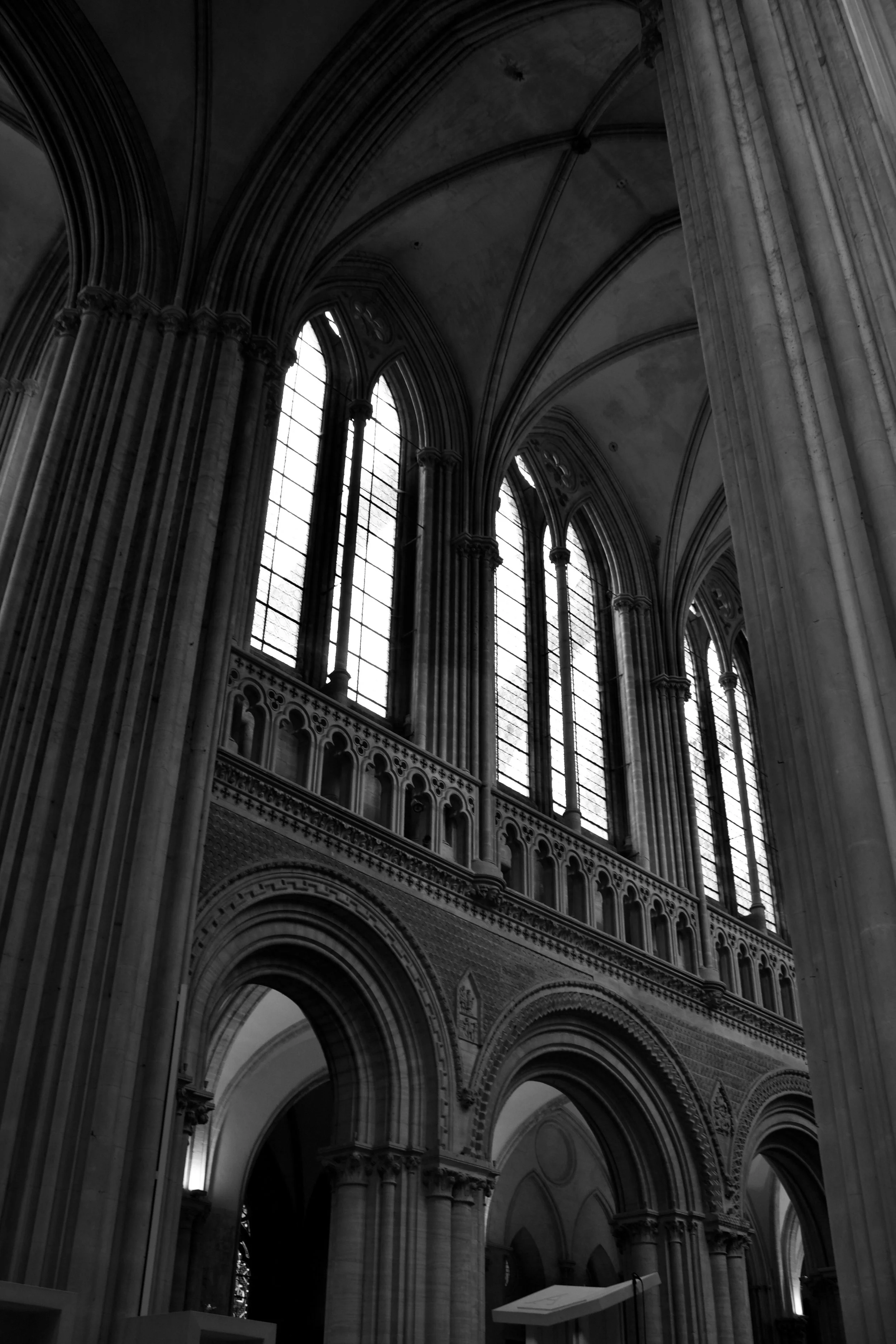 Interior of a Gothic cathedral with tall, stained glass windows and ornate stone arches.