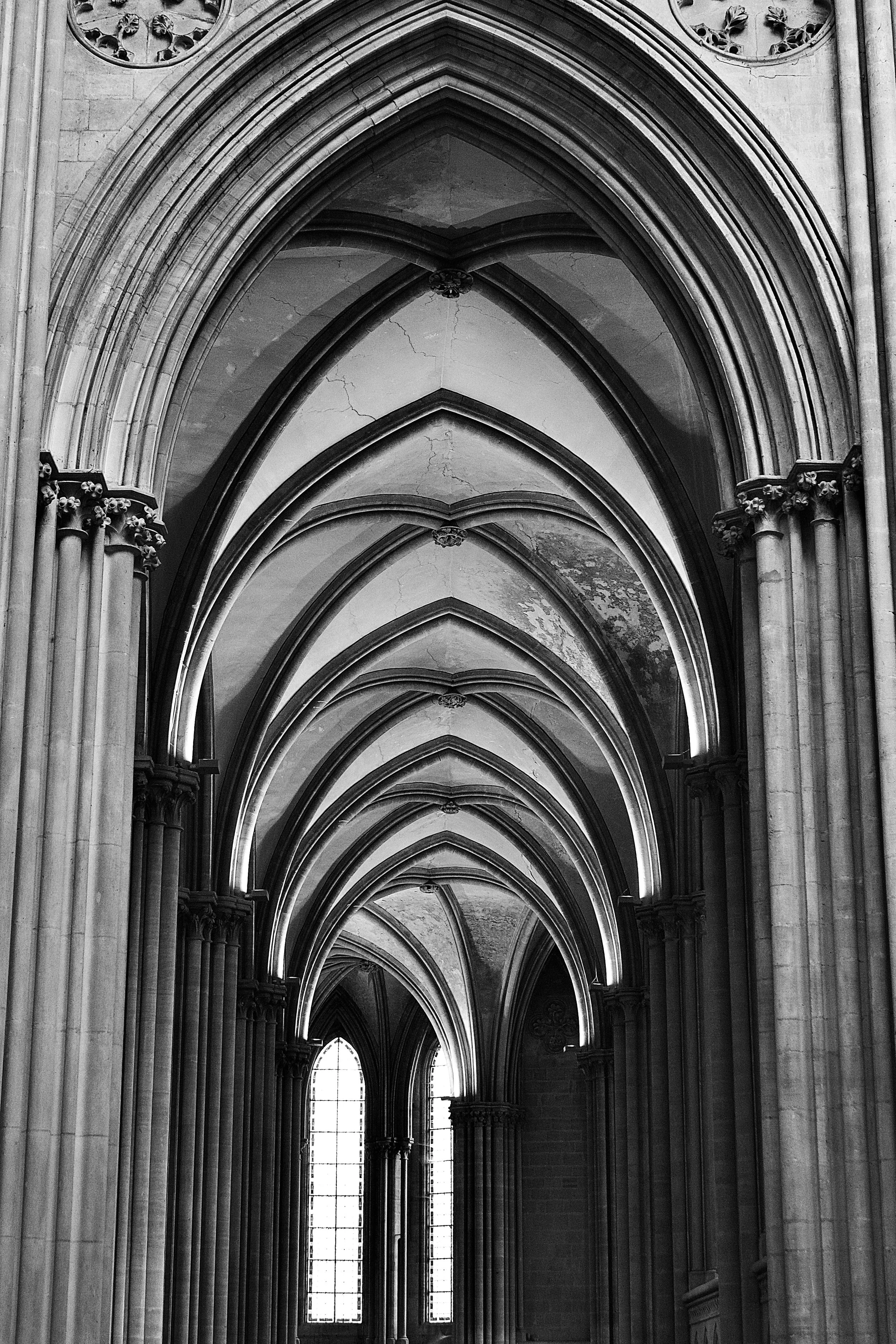 Black and white photo of church interior with pointed arches, columns, and stained glass windows.