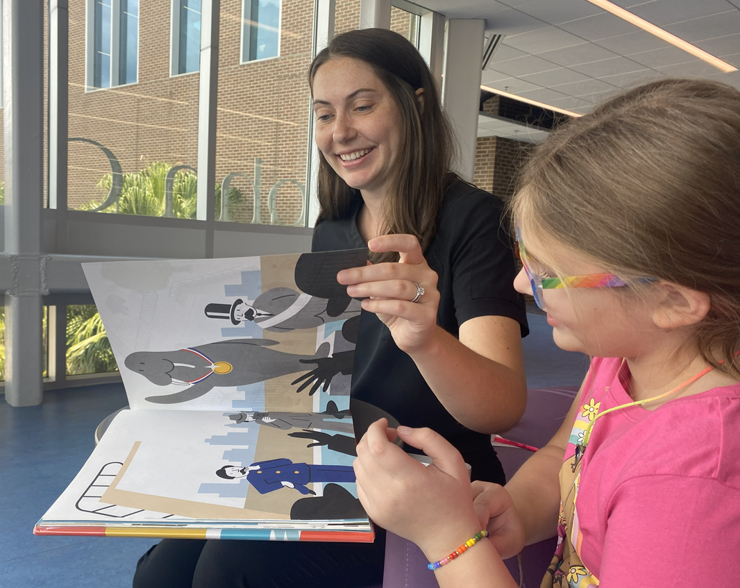 A photo of a speech-language pathologist and a child looking at a picture book.