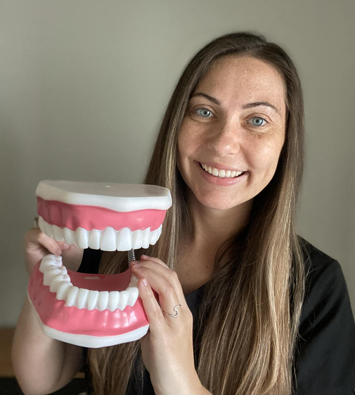 A photo of a speech-language pathologist holding a toy shaped like a mouth.