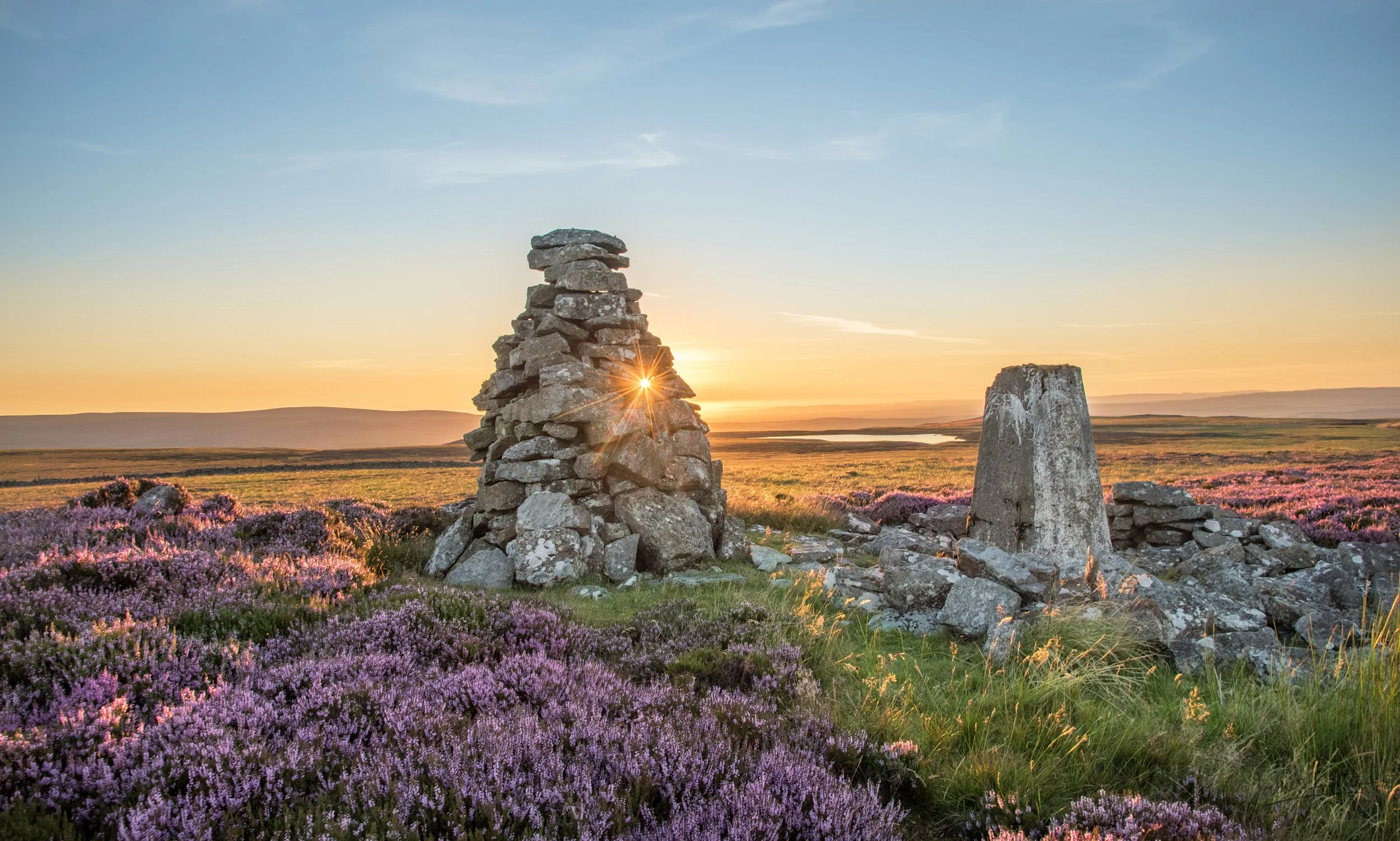 Pikerigg currick and Trig Point near Whitfield lough during a summers evening with the heather in bloom