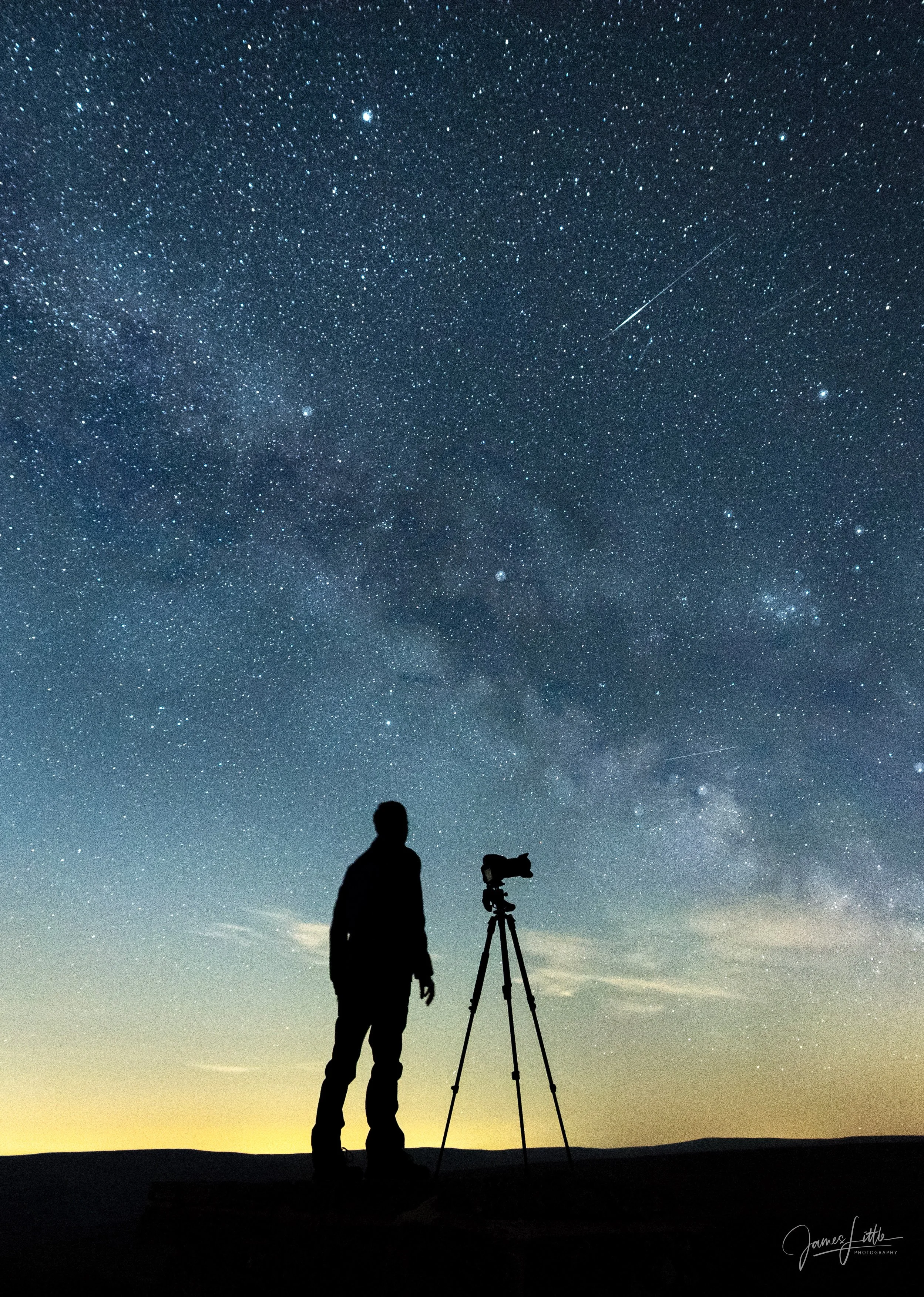 Silhouette of a person standing next to a telescope under a star-filled night sky with the Milky Way visible.
