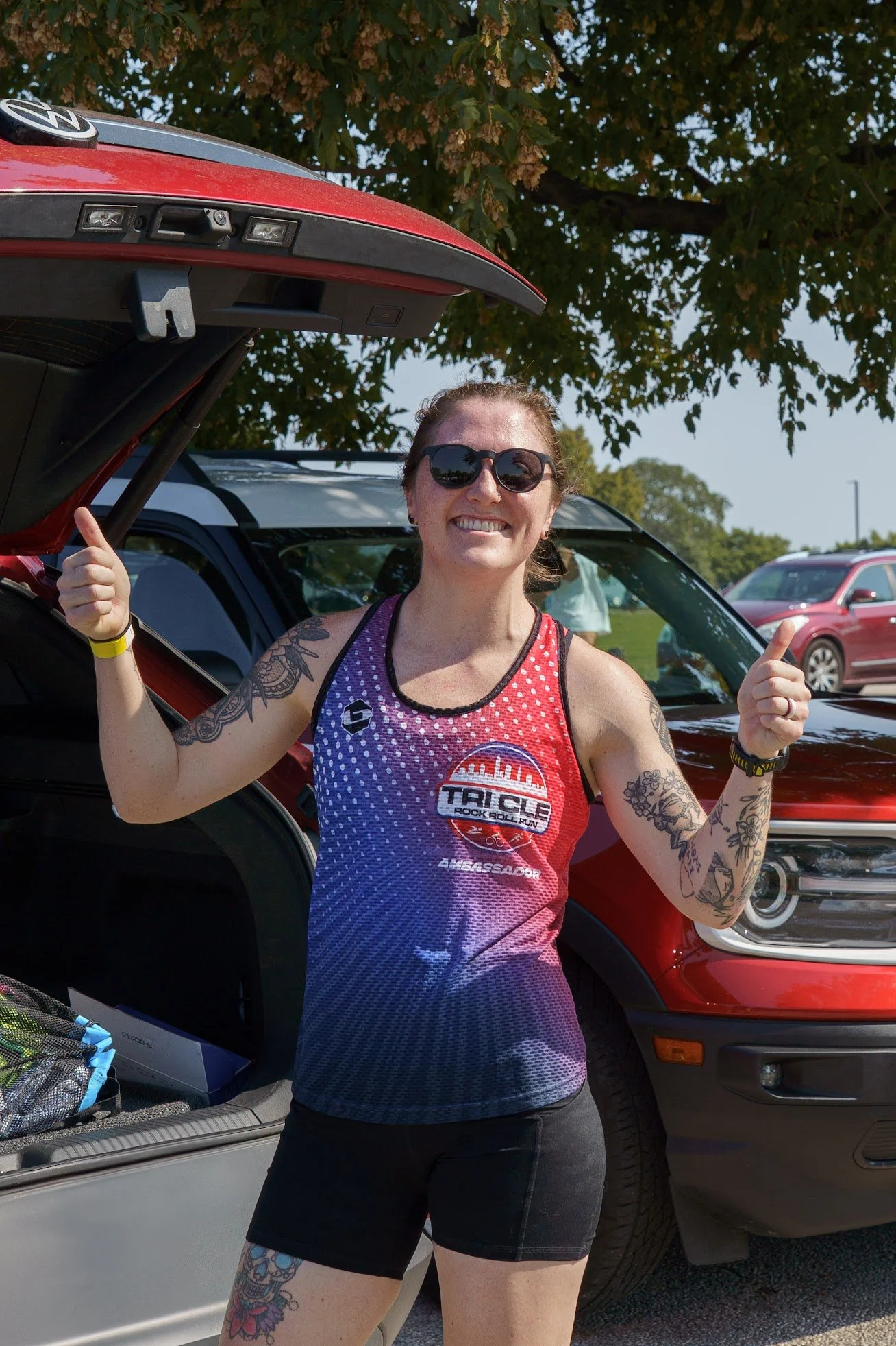 Ambassador Elise in her ambassador tank standing behind her car.