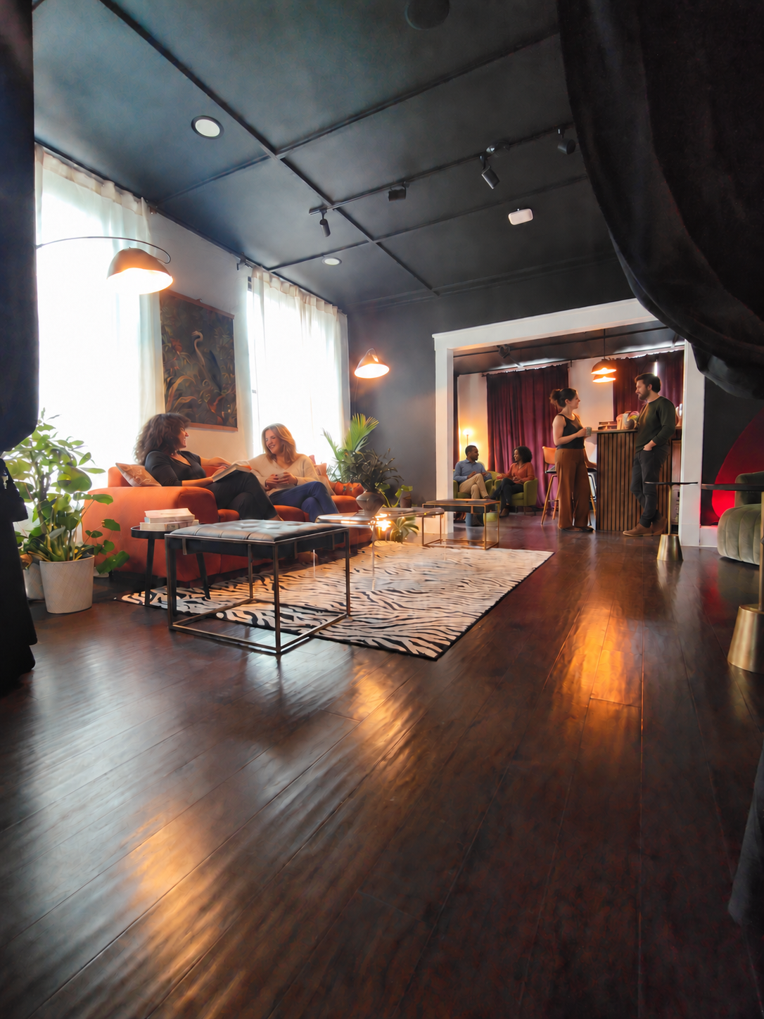 Analog Room lounge with an orange sofa, green chairs, plants, and a bar