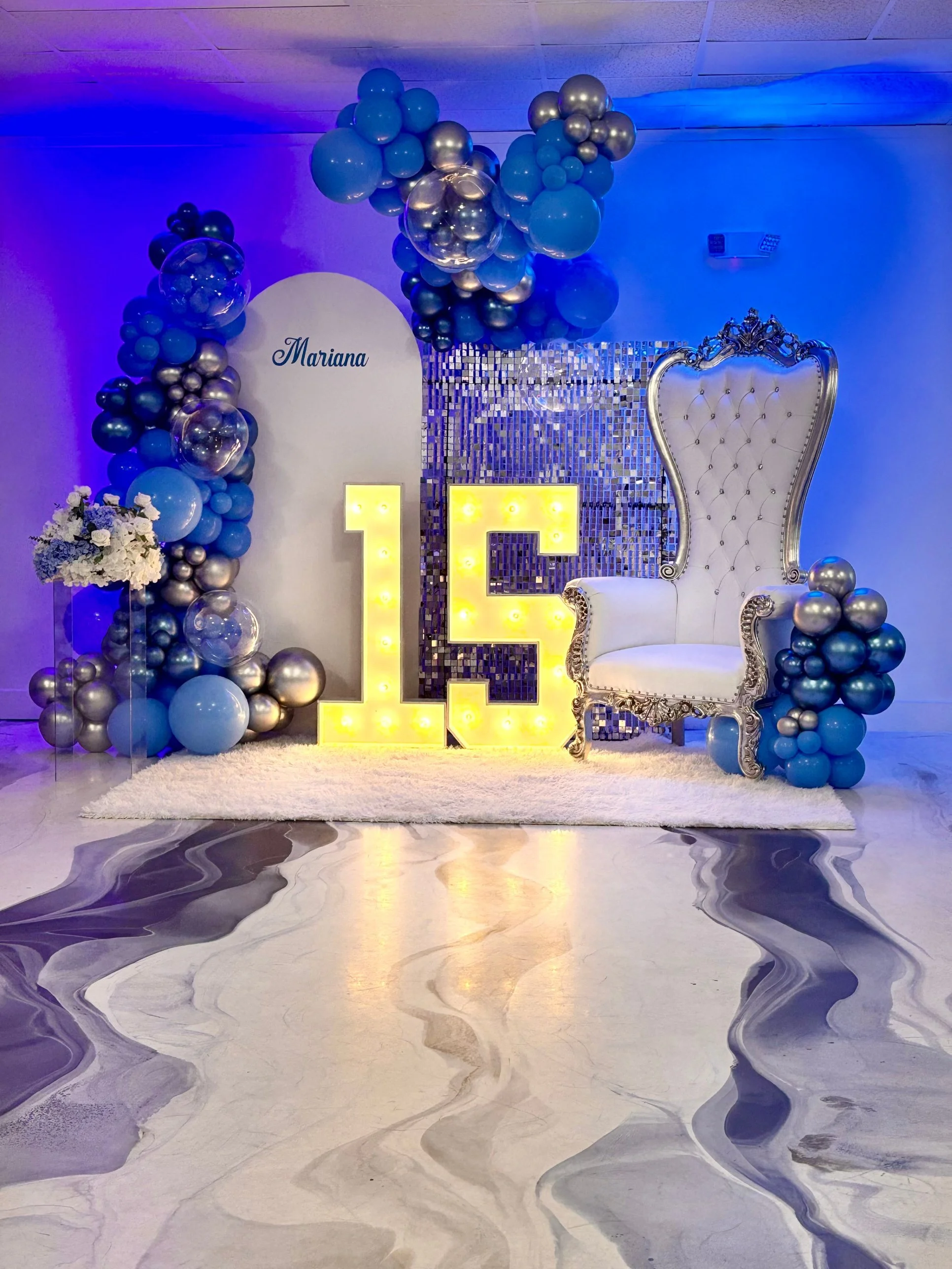 Blue and silver quinceañera balloon backdrop with marquee 15 lights and throne chair at La Mercedes Events