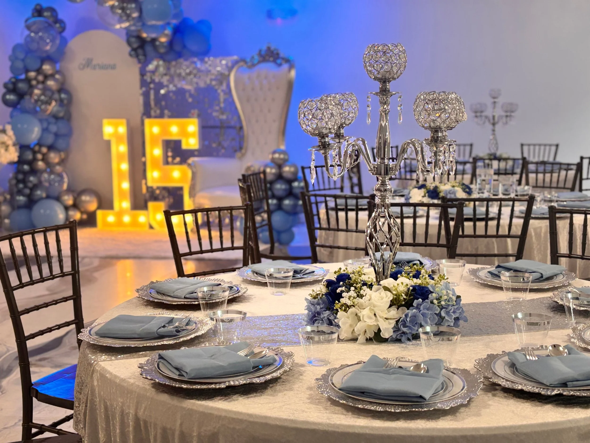 Quinceañera table setting with crystal candelabra centerpiece and dusty blue napkins at La Mercedes Events