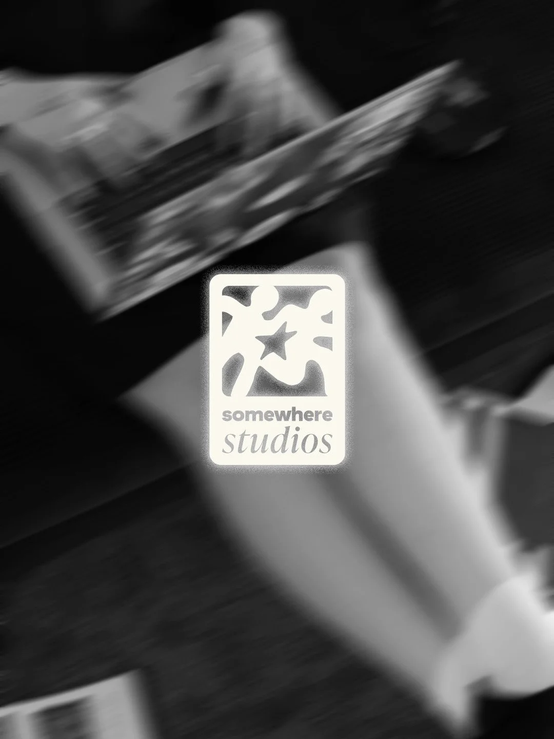 A blurred black-and-white photo of a plant next to a logo of 'somewhere studios' with a star and abstract shapes, on a dark background.
