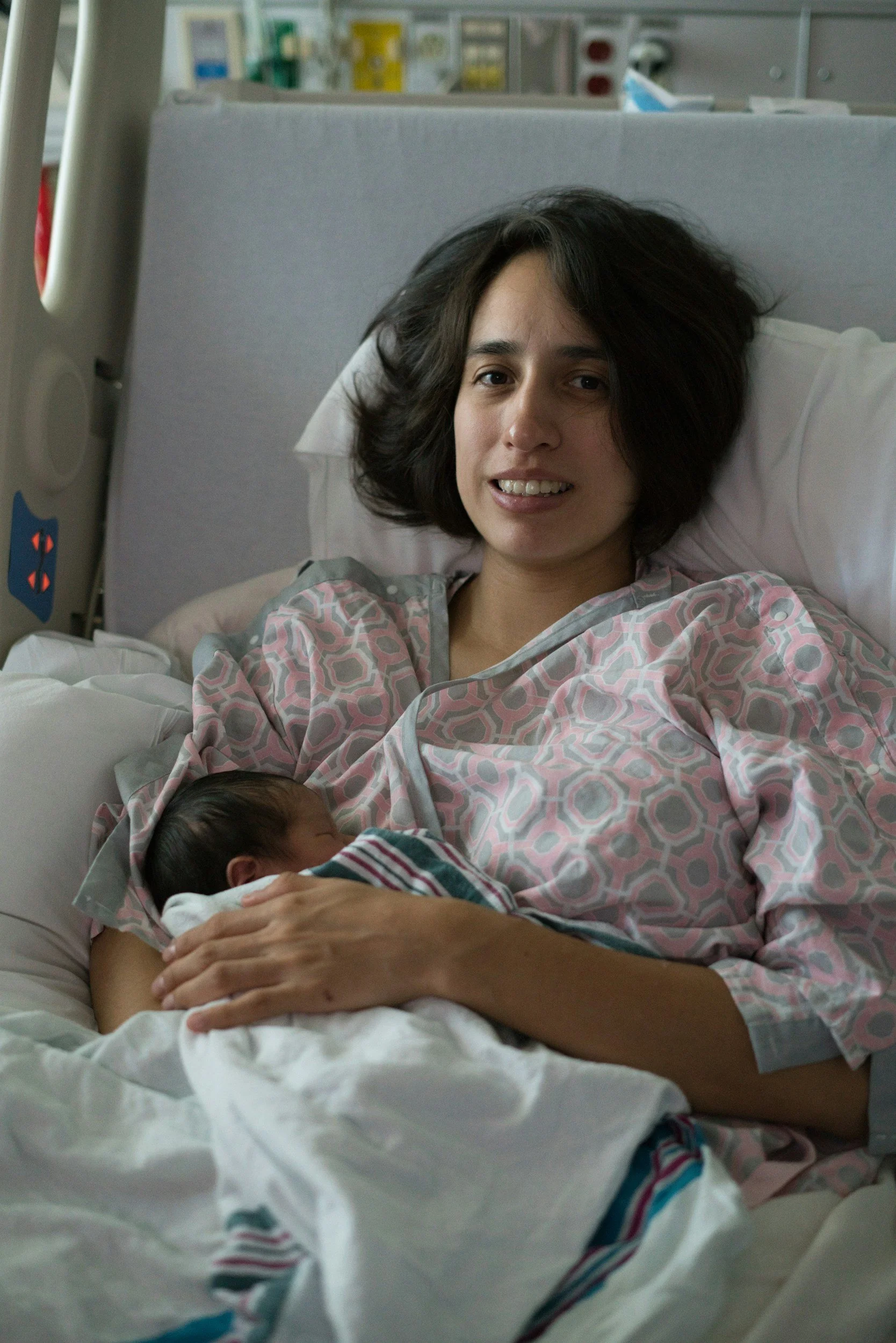 A woman lying in a hospital bed holding a newborn baby.
