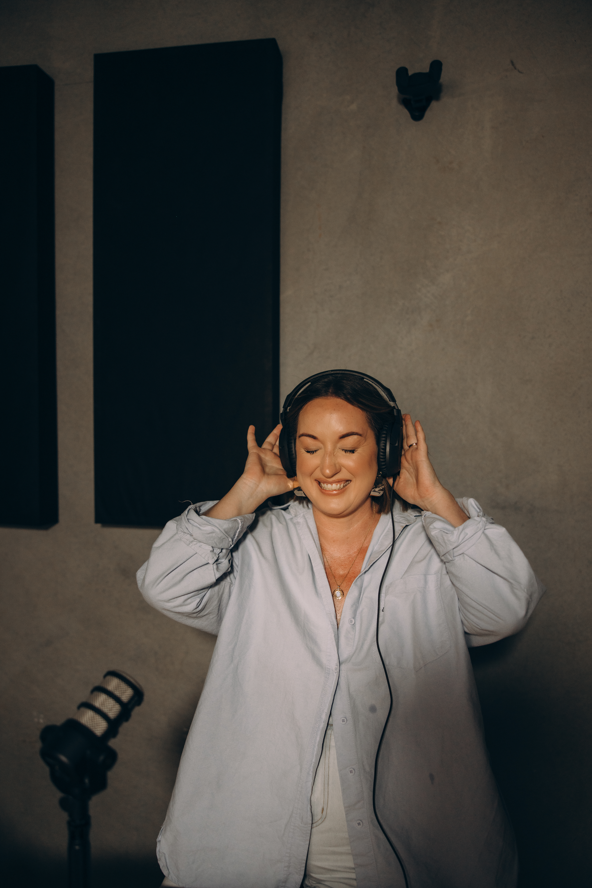 Ash Becker wearing headphones in a recording studio doing Podcast | Career Coach in Australia