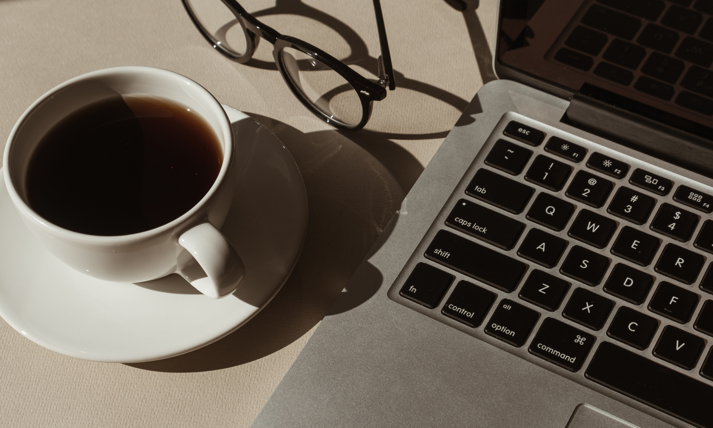 A cup of black coffee and a pair of sunglasses with a laptop for women in career