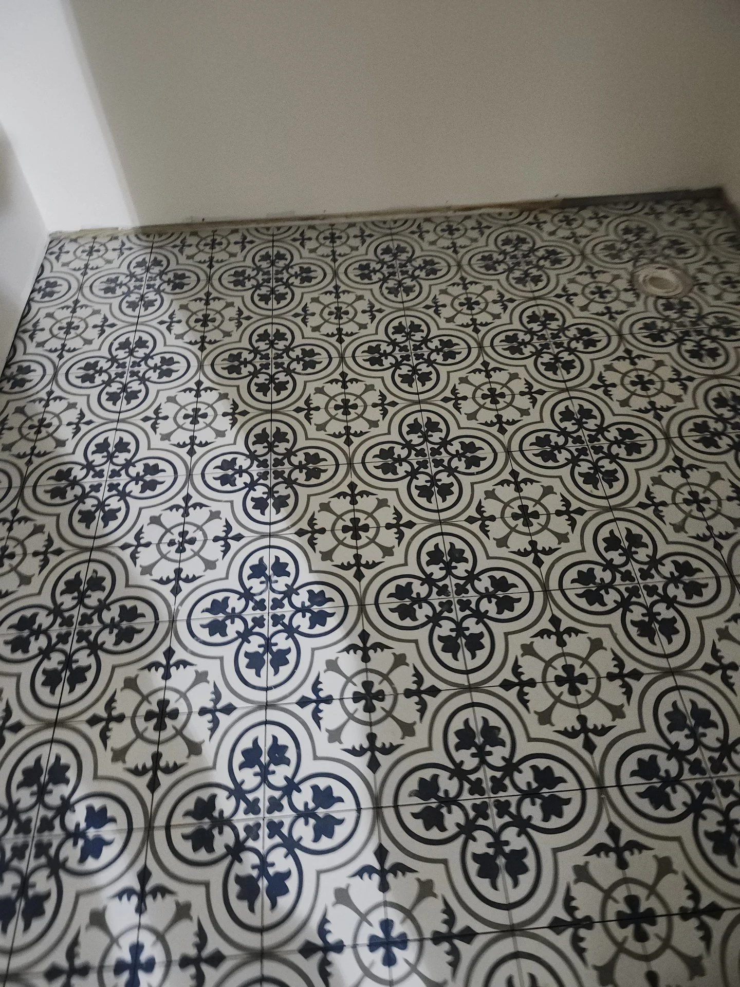 Floor with black and white patterned tiles featuring intricate floral and geometric designs.