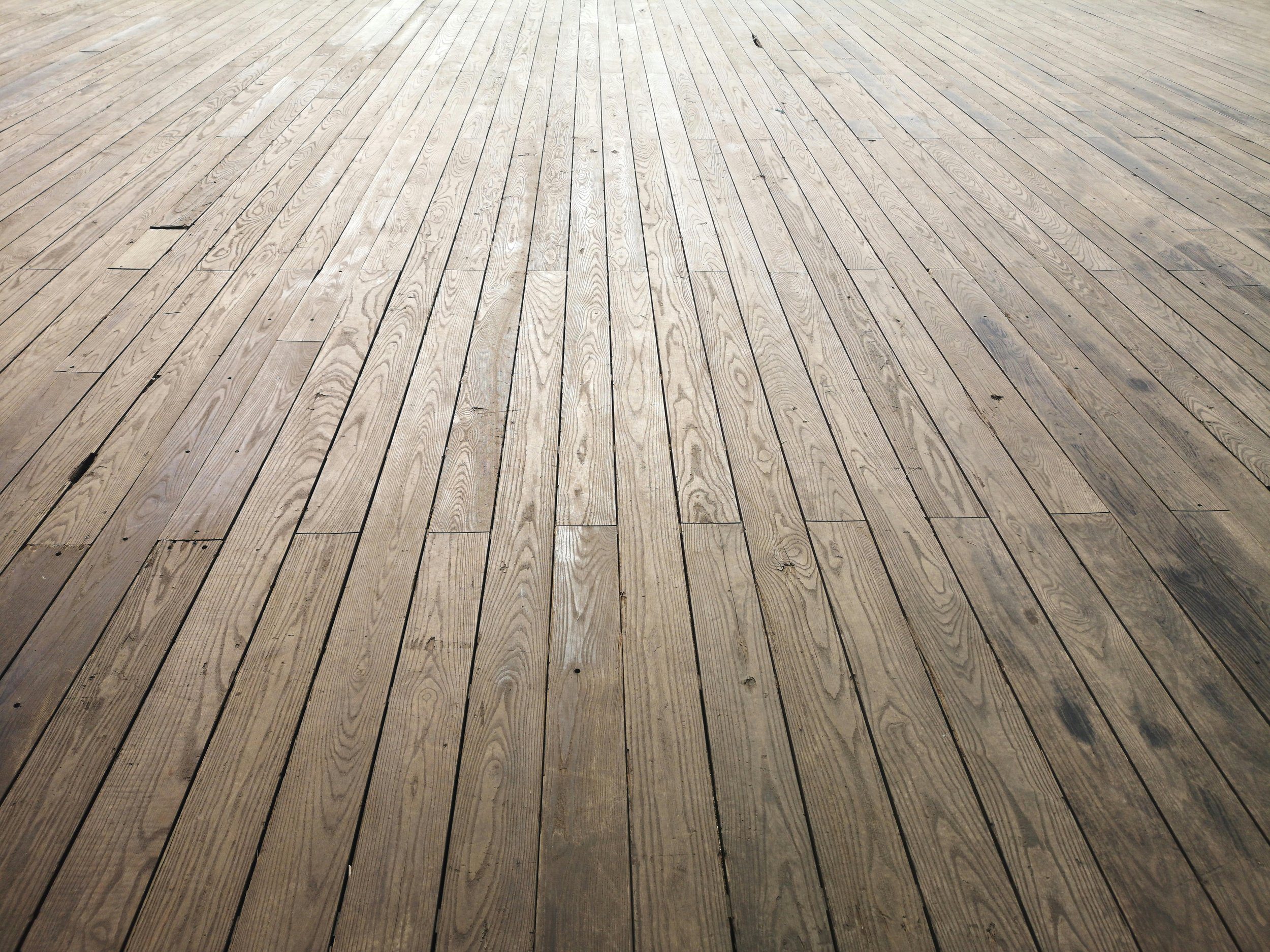 Wooden deck flooring with evenly spaced planks, some showing knots and slight discolorations.
