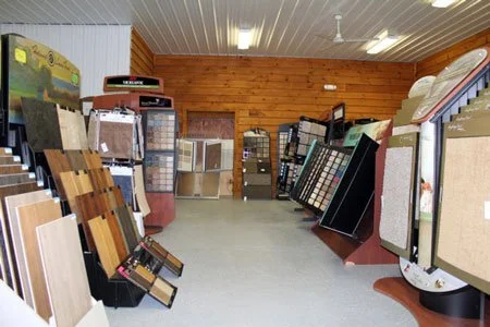 Interior of a store displaying various flooring samples and tiles on racks and shelves.