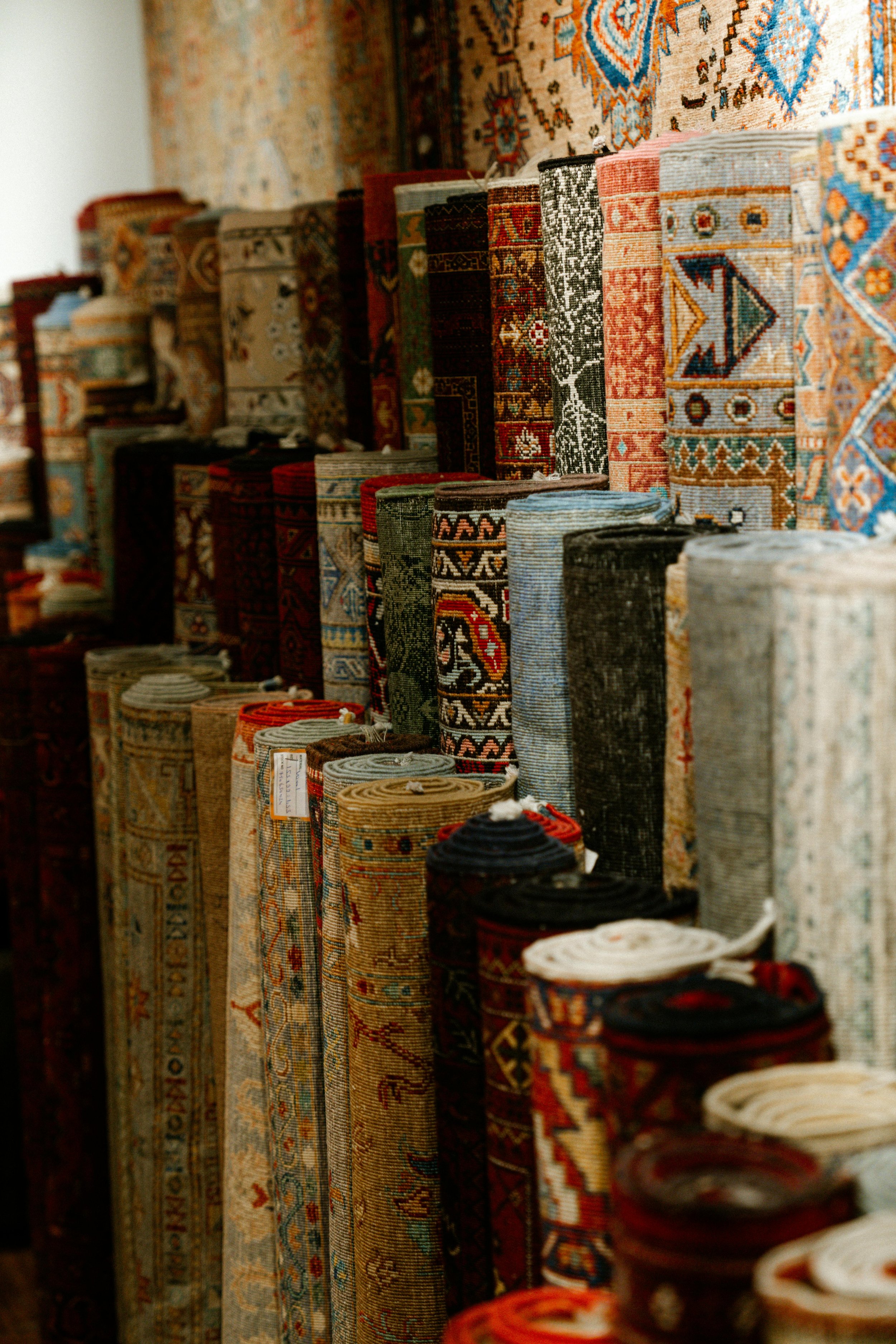 A collection of rolled and folded Persian rugs displayed in a store.