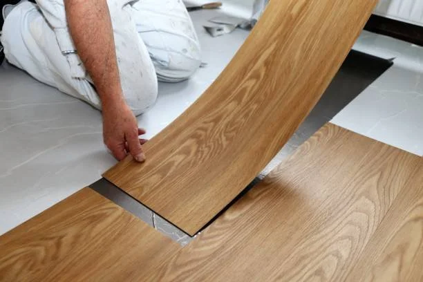 Person installing wooden flooring with interlocking planks.