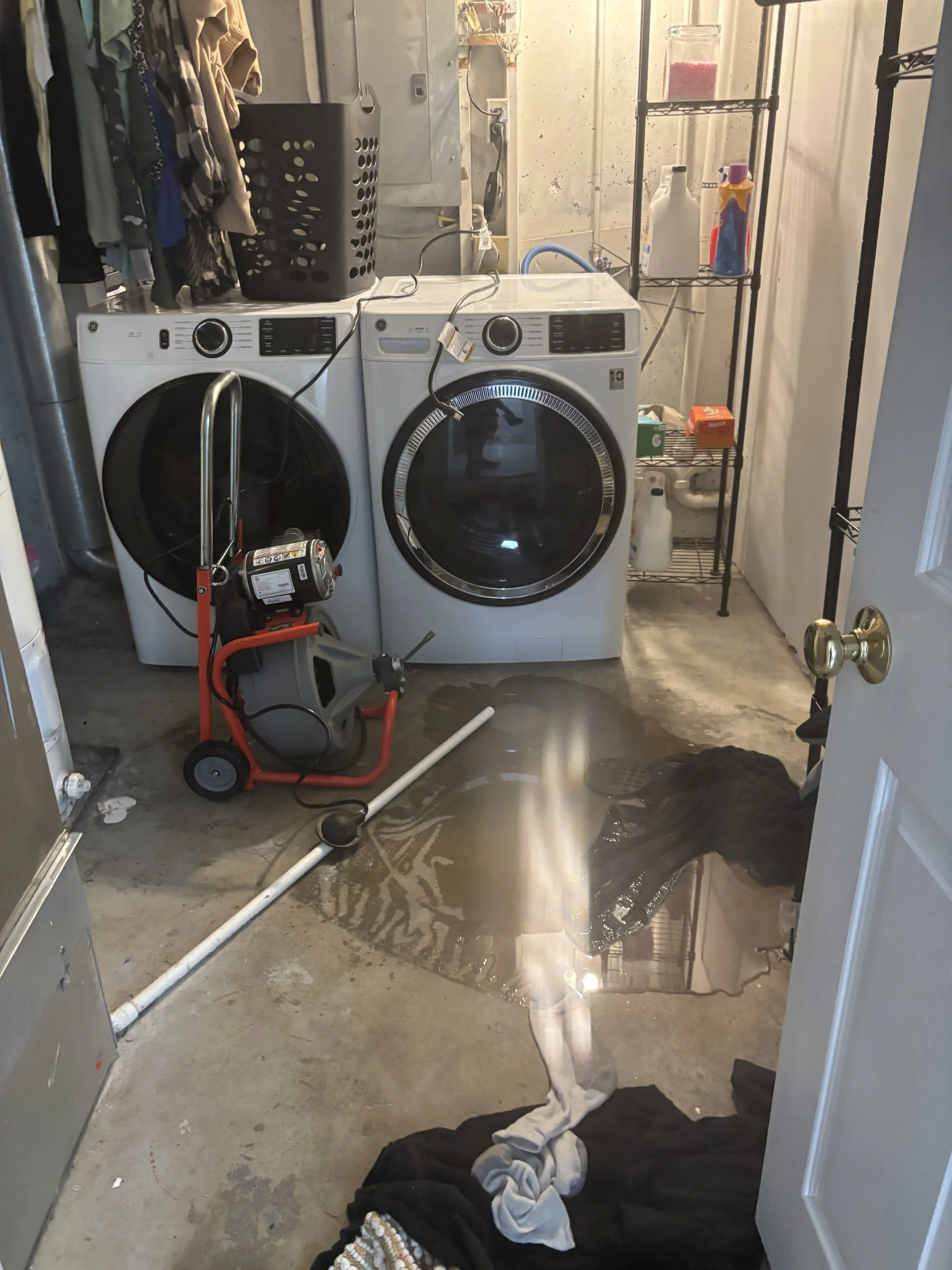 A laundry room floor drain backing up, Sewer machine in the room staged ready to clear the clog.