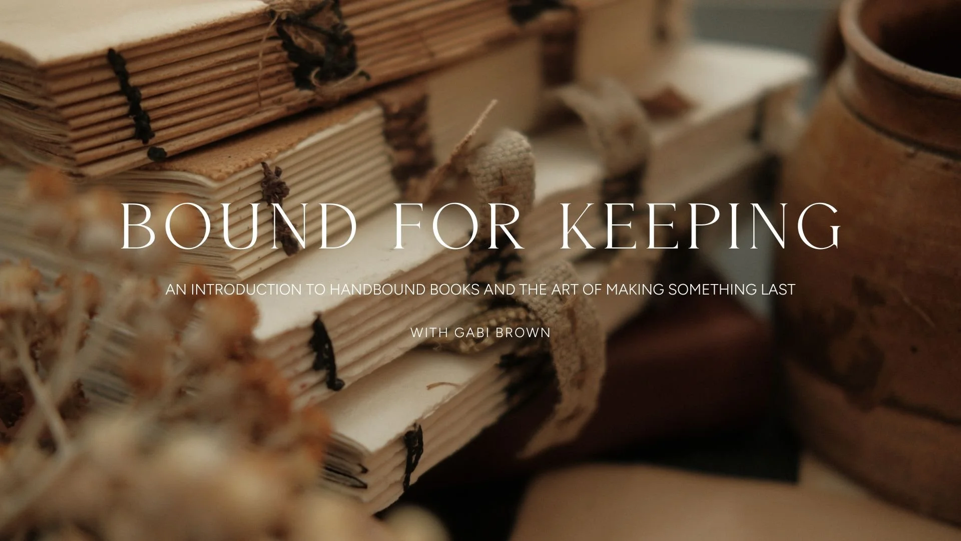 Close-up of vintage handbound books, string-tied, with a clay pot in the background.