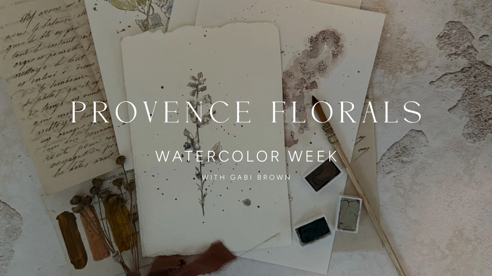 Painting supplies arranged on a textured surface, featuring watercolor paints, brushes, and botanical sketches related to Provence floral themes for watercolor week.