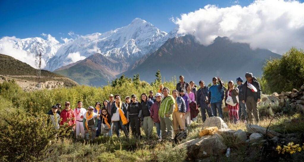 Group of hikers standing outdoors in a mountainous area with snow-capped peaks in the background in the Himalayas in the Annapurna Area.