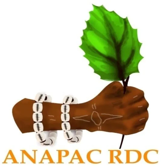 A fist holding a green leaf with several white beads wrapped around the wrist and forearm, featuring a tattoo of a bird on the arm, and the text 'ANAPAC RDC' below.
