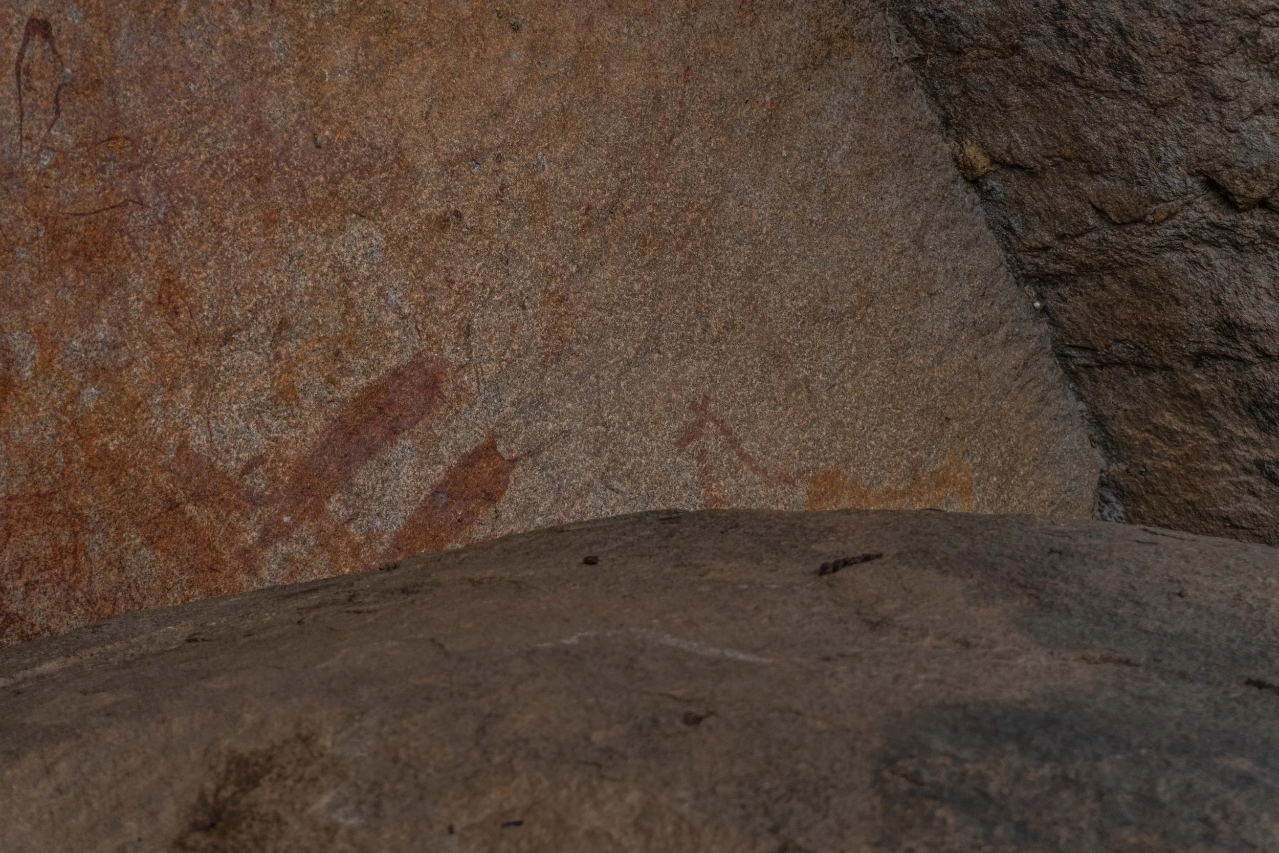 Close-up of ancient cave wall with faded petroglyphs or cave paintings.