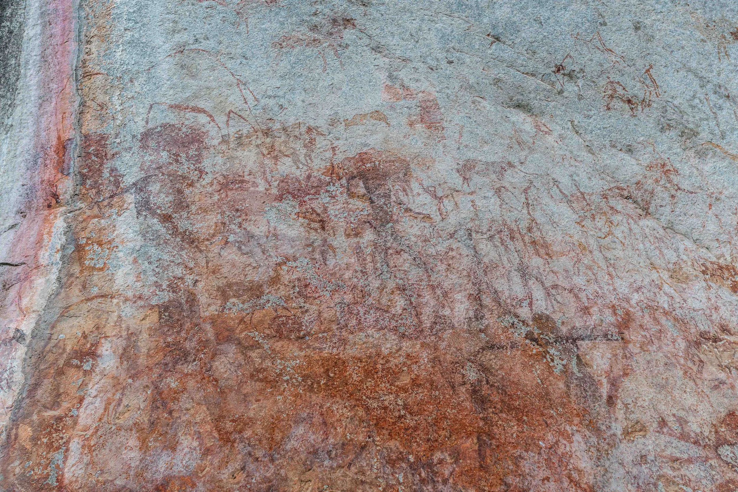 Prehistoric cave painting of animals on a rock wall being affected by erosion.