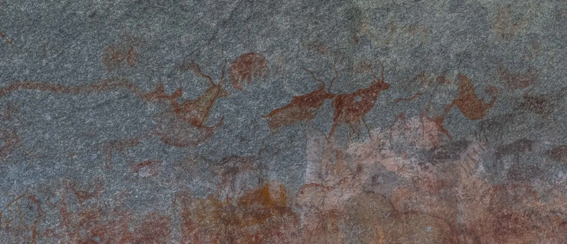 Prehistoric cave painting of human figures and animals, likely depicting hunt scene, on a rock wall.