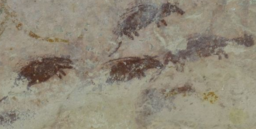 Faded ancient cave painting of porcupines on a rocky wall.