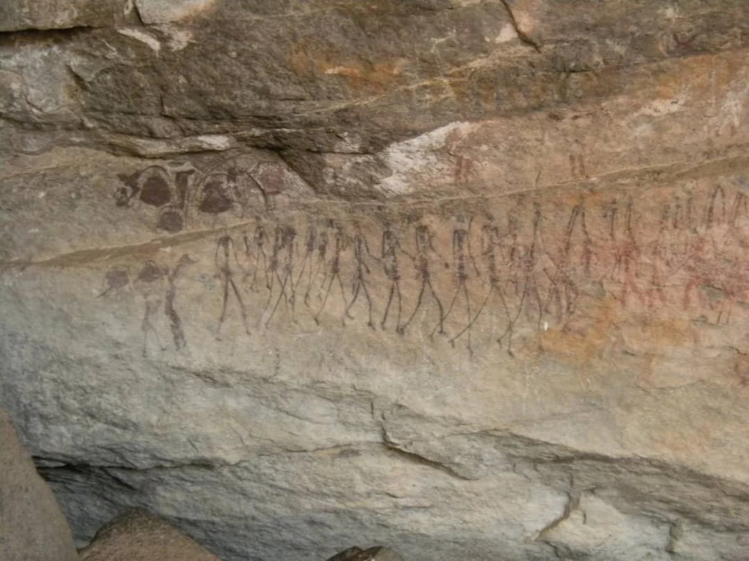 Ancient cave painting of human figures holding hands in a procession