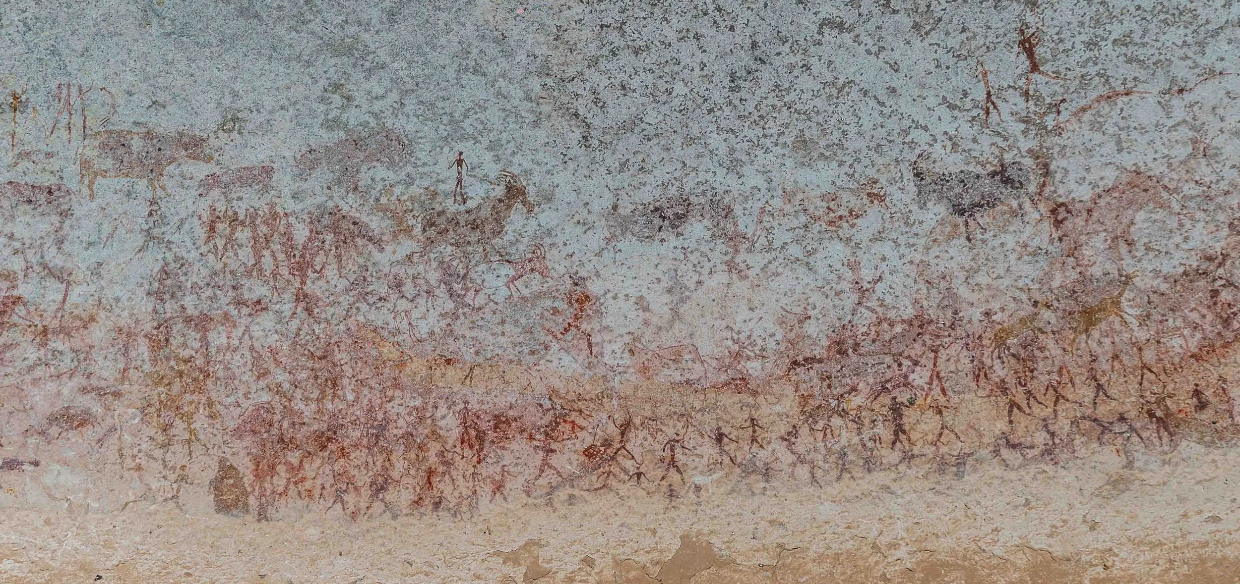 Prehistoric cave painting depicting animals, human figures, and primitive symbols.