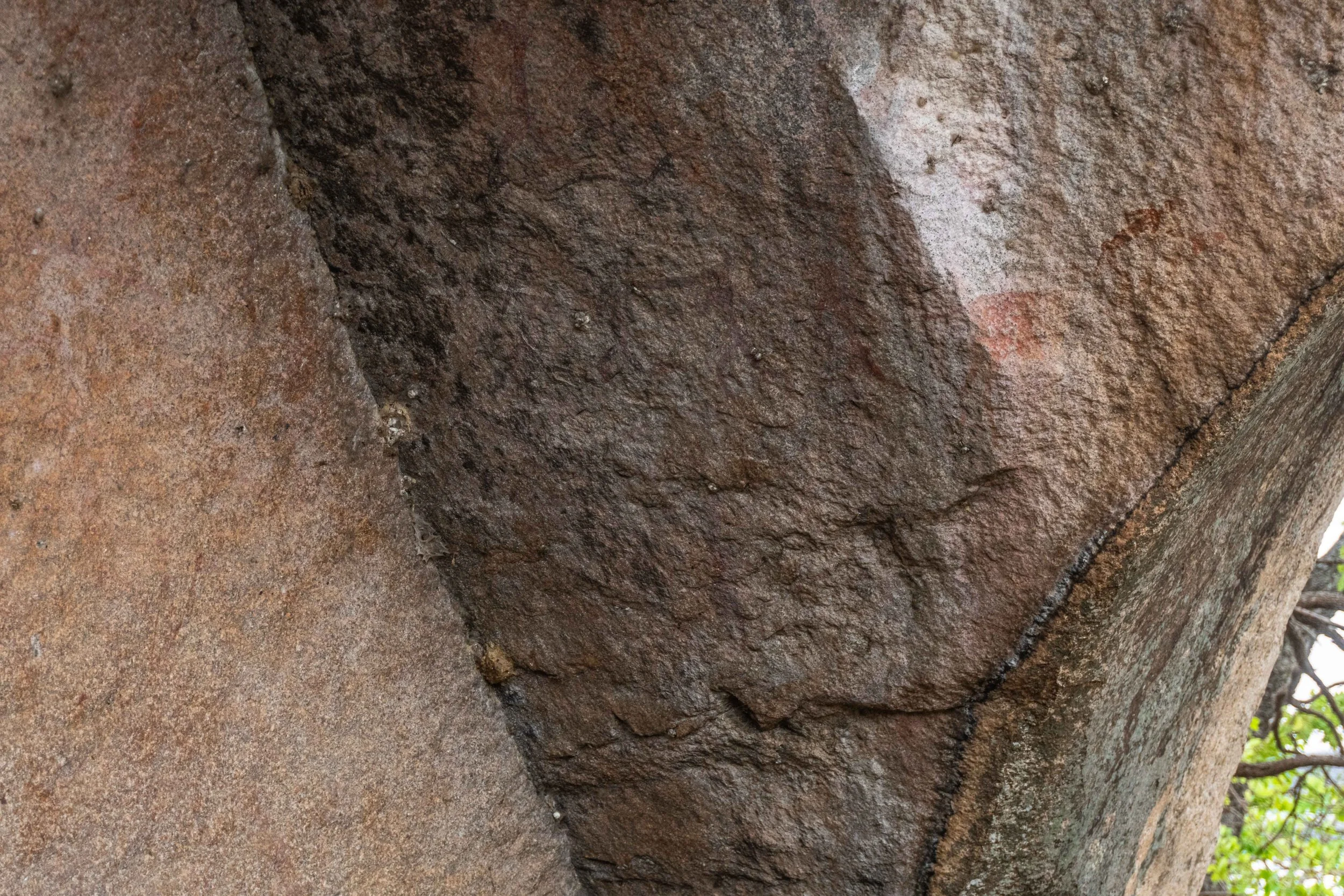 Close-up of a weathered brown stone wall with visible textures and cracks.
