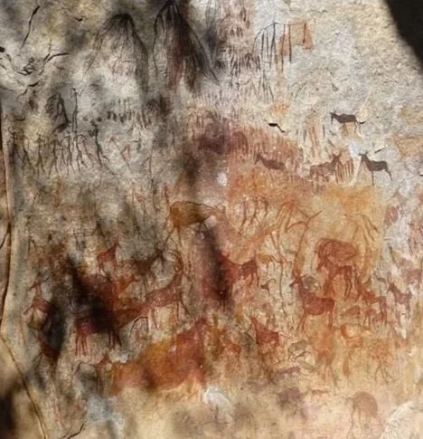 Prehistoric cave paintings with human and animal figures.