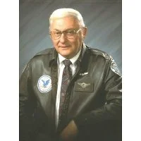 Portrait of an elderly man with glasses wearing a police uniform and a leather jacket.