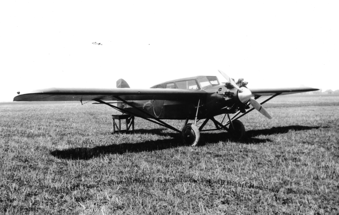 Black and white photo of a vintage propeller airplane on a grassy field.