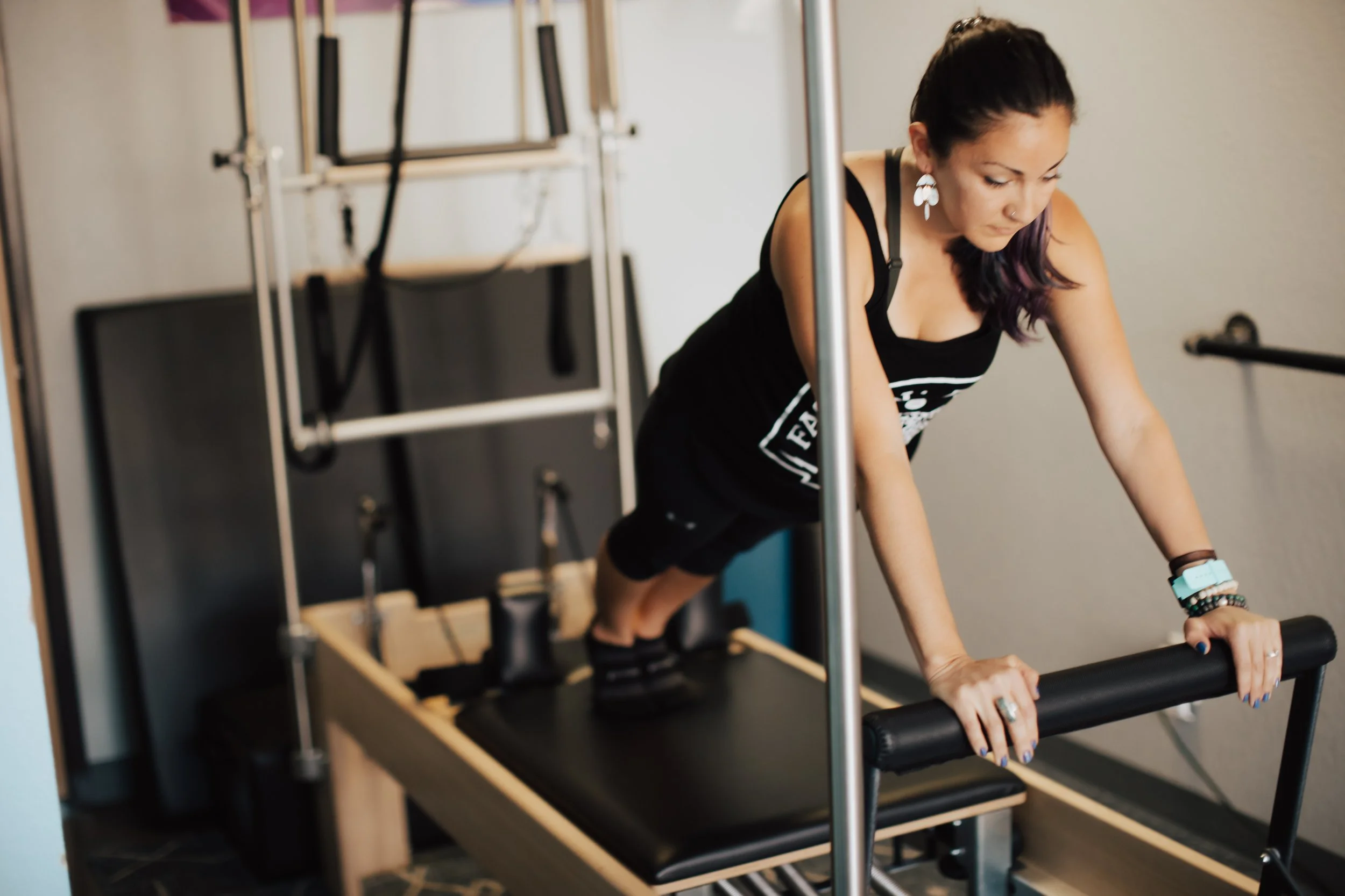 woman wearing all black doing a plank on a Pilates reformer