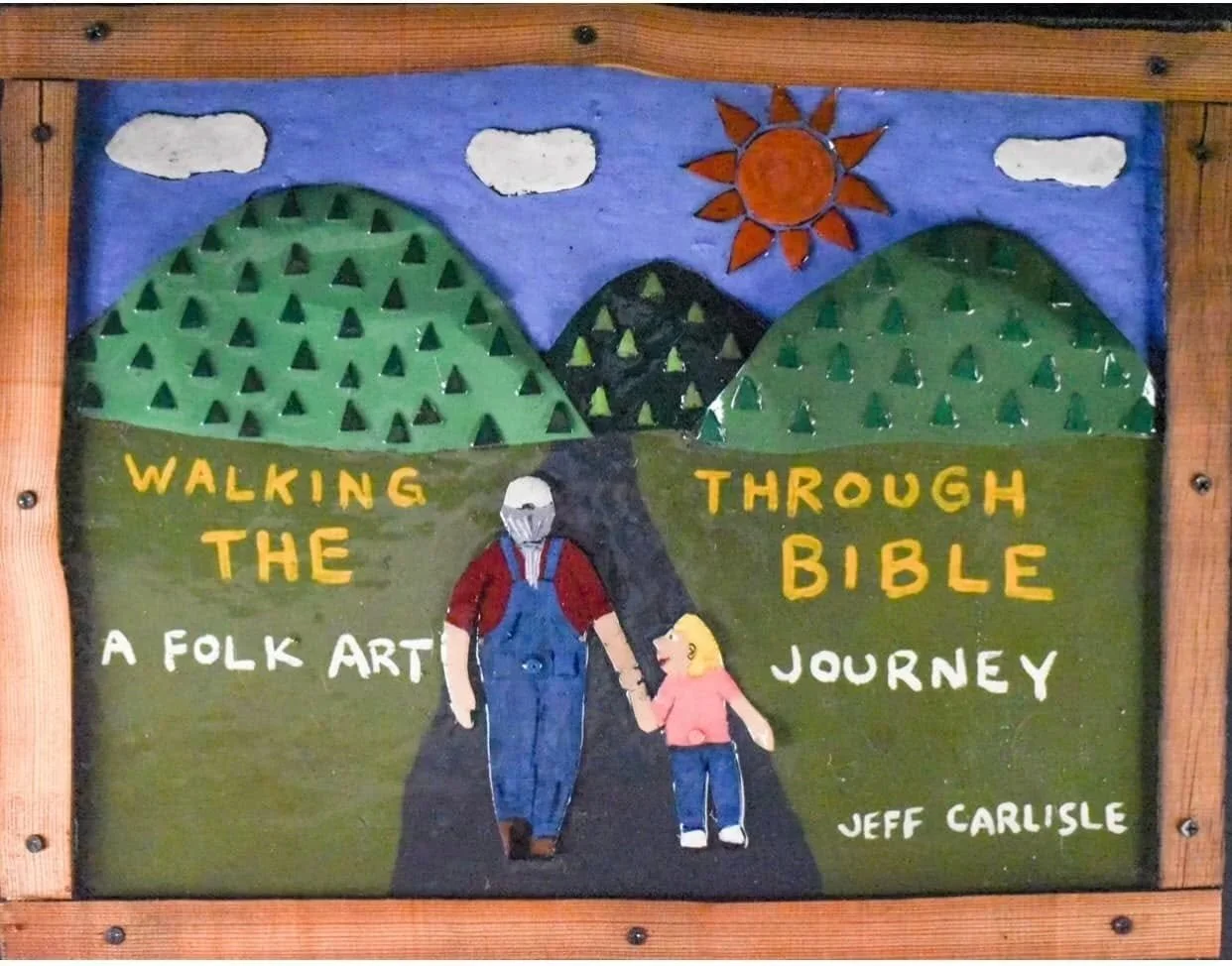 Folk art sign titled 'Walking Through the Bible: A Folk Art Journey' by Jeff Carlisle. Depicts mountains, a sun, clouds, and two figures walking hand in hand.
