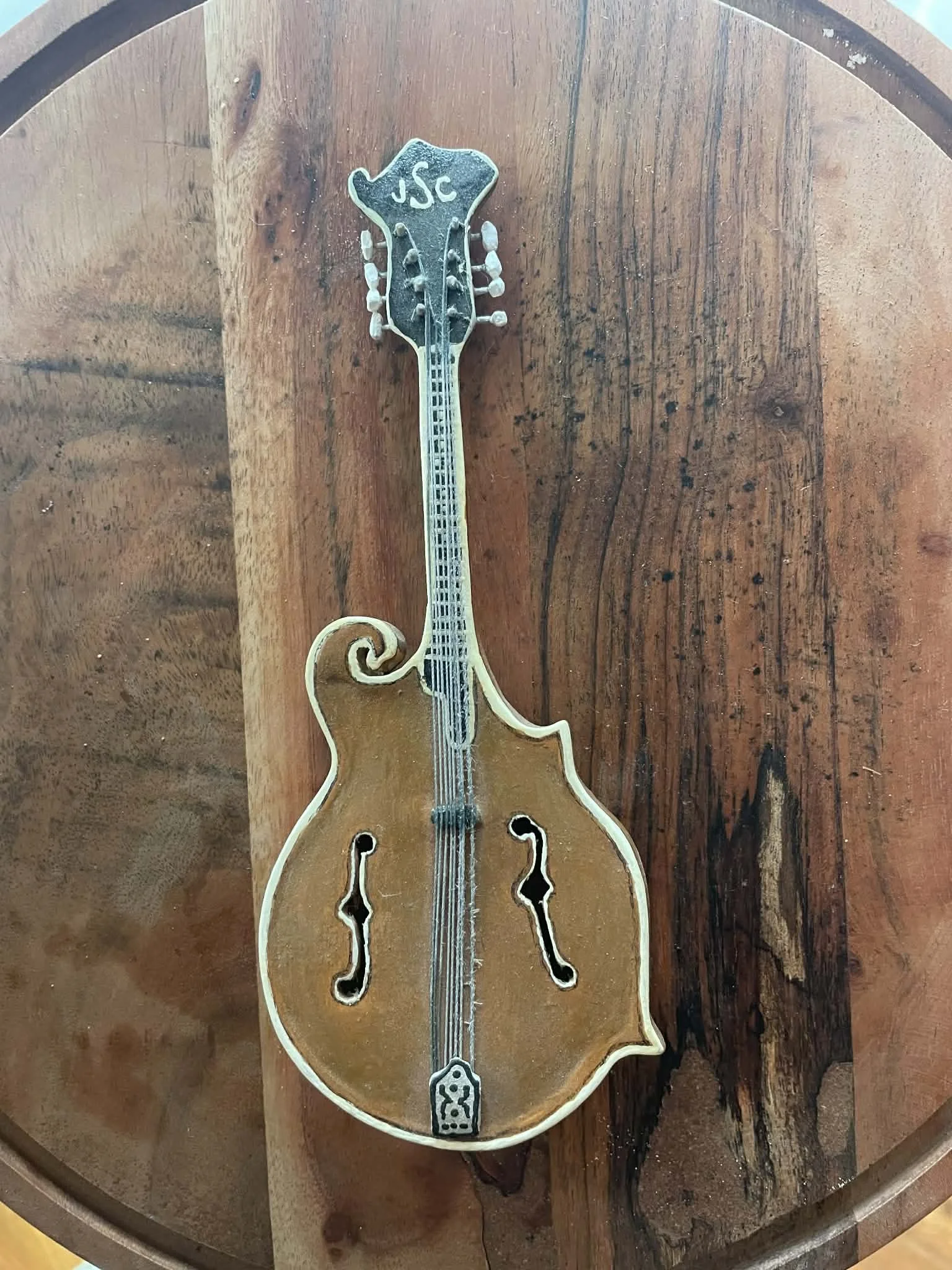 A decorative wooden cutout of a violin placed on a round wooden table.
