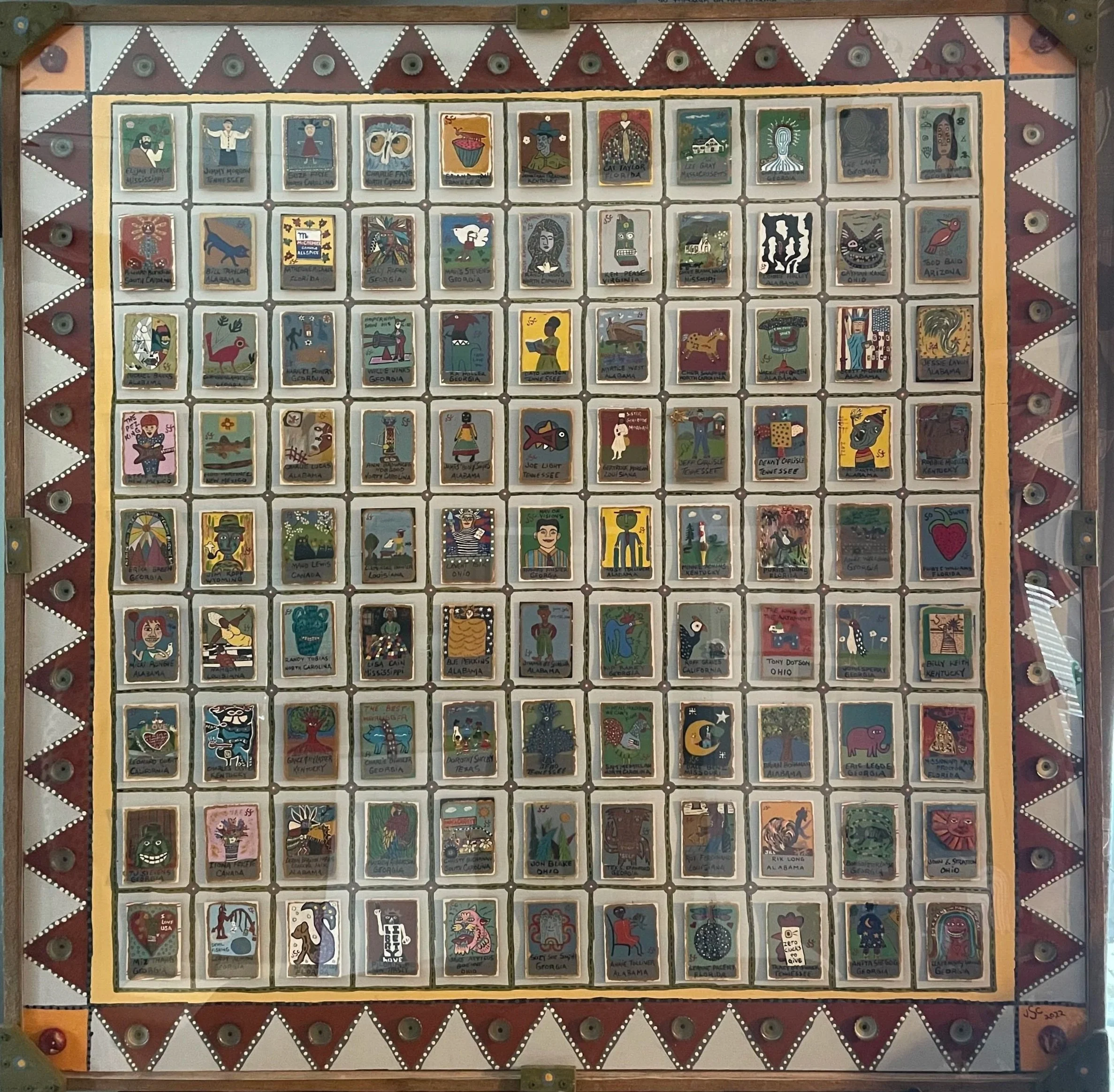 A framed collection of painted tiles, each depicting various symbols, animals, and figures representing different U.S. states, arranged in a grid pattern.