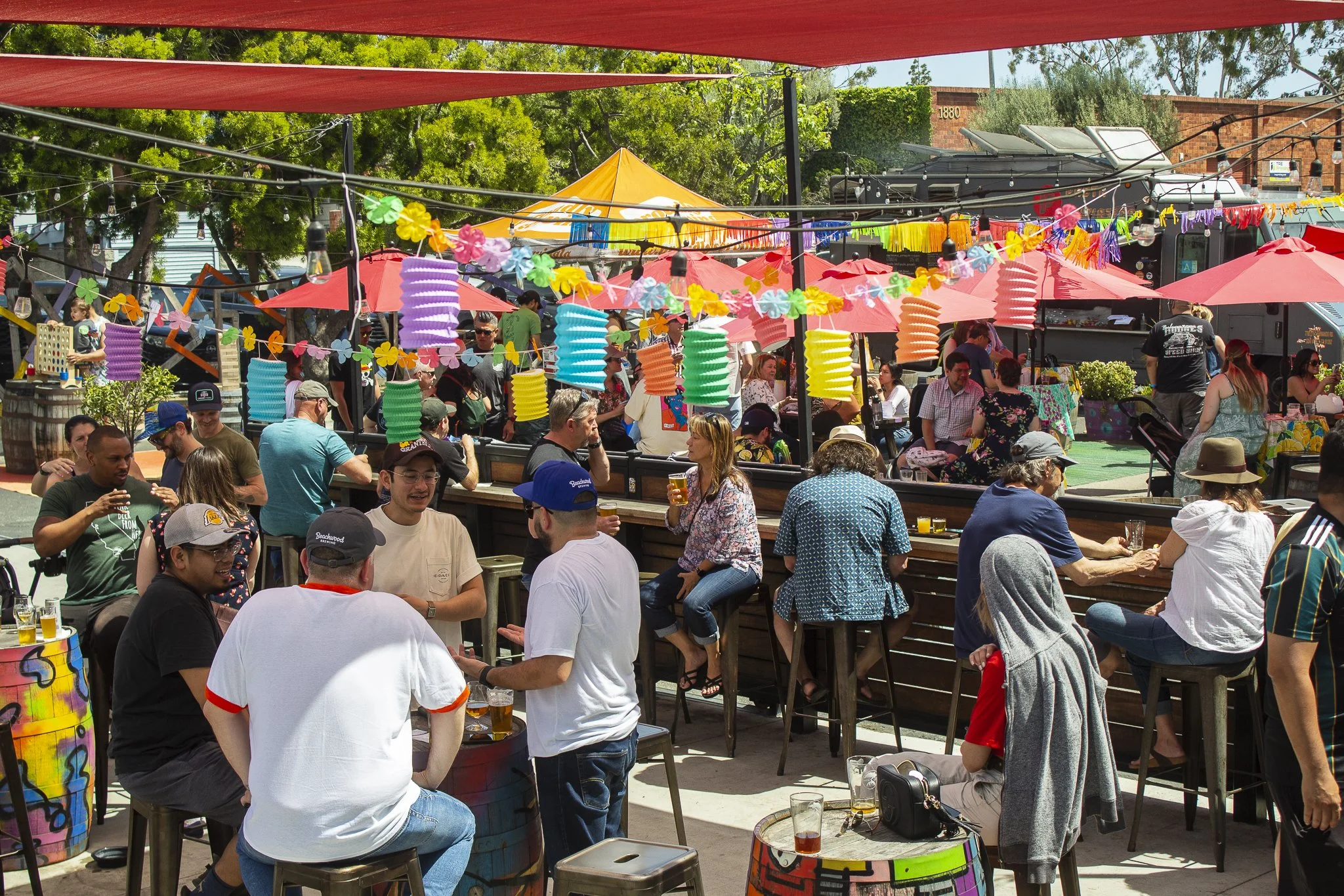 Groups of guests sitting outside on the Smog City patio with colorful decorations overhead.